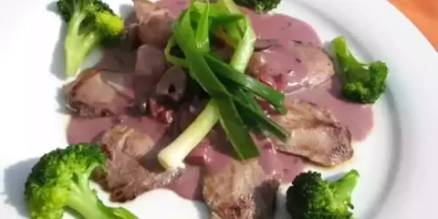 Tranches de viande en sauce rosée, accompagnées de brocolis et d'oignons verts. Une bonite recette à essayer !
