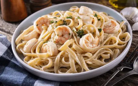 Délicieuses pâtes aux crevettes, une recette italienne crémeuse et savoureuse, garnie de persil frais.