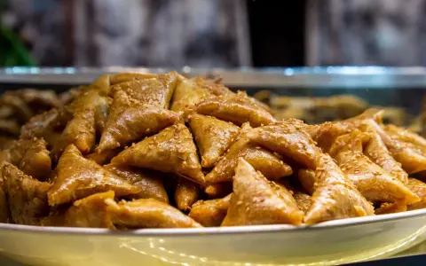 Un plateau rempli de délicieux triangles dorés, un dessert marocain traditionnel, parsemé de graines de sésame.
