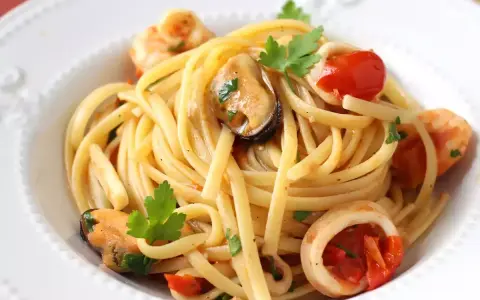Spaghetti aux fruits de mer à la crème, garni de moules, crevettes, calamars, tomates cerises et persil frais. Un délice crémeux et savoureux.