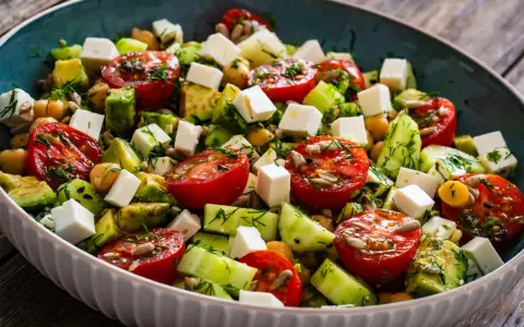 Salade colorée avec tomates, avocat, concombre, pois chiches et cubes de feta. Une recette fraîche et légère, parfaite pour un repas d'été.