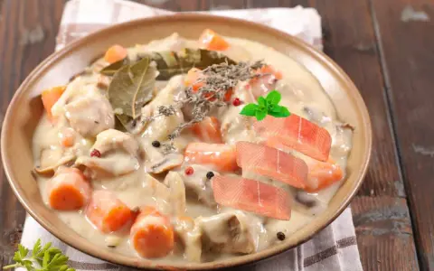 Délicieuse blanquette de poisson crémeuse avec carottes, champignons, herbes et garnie de tranches de saumon frais.