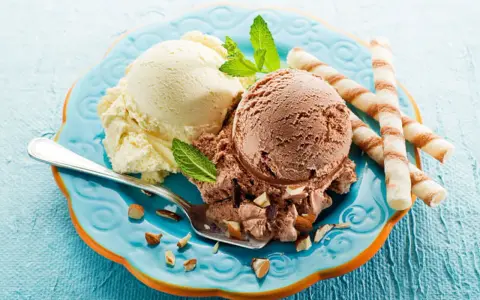 Glace italienne maison sans machine : deux boules vanille et chocolat, garnies d'amandes et de menthe, avec des gaufrettes.