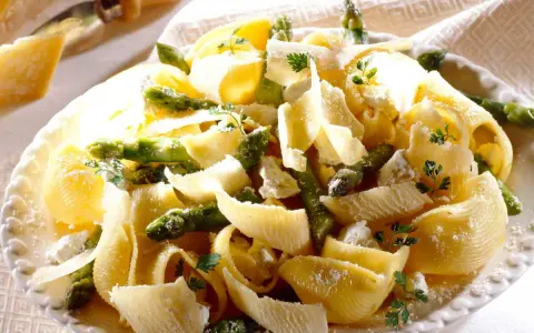 Pâtes aux asperges, garnies de copeaux de parmesan et de persil frais. Un plat printanier savoureux.