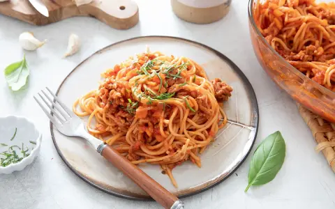 Une assiette de spaghetti à la bolognaise, plat réconfortant de one pot pasta, garnie d'herbes fraîches.