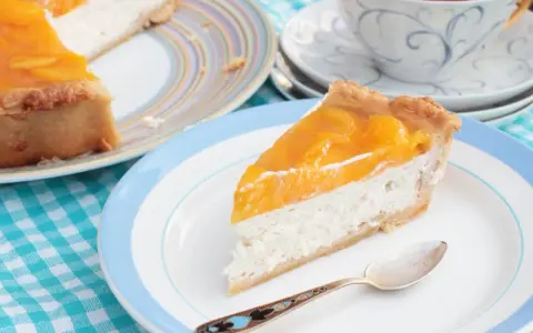 Tranche de cheesecake aux pêches, une gourmandise légère. L'agar agar, son utilisation, assure une texture parfaite.