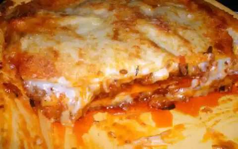 Une part généreuse de lasagne à la viande hachée, avec sa couche de fromage gratiné et sa sauce tomate débordante. Un délice réconfortant.