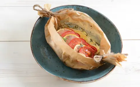 Poisson cuit en papillote avec tomates et citron, une recette bar simple et savoureuse.