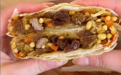 Une délicieuse pastilla agneau, coupée en deux, révèle sa garniture généreuse de viande, raisins secs, pignons et carottes.