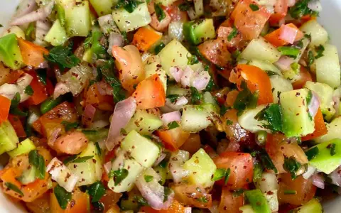Salade marocaine fraîche et colorée, mélange de tomates, concombres, oignons rouges et persil, assaisonnée d'épices.