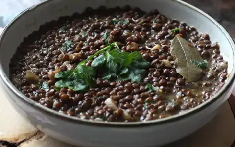 Un plat de cuisson lentilles vertes, garni de persil frais et d'une feuille de laurier. Un délice simple et réconfortant.