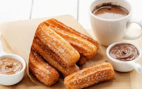 Churros dorés et croustillants, saupoudrés de sucre, prêts à être trempés dans le chocolat. Une recette gourmande pour un goûter parfait.