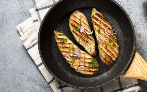 Aubergines grillées dans une poêle, garnies d'oignons rouges et de persil. Une délicieuse recette aubergine prête à être dégustée.
