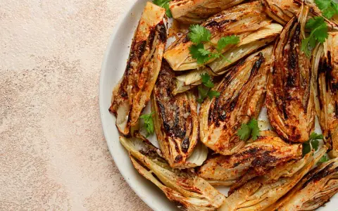 Fennouil rôti, coupé en quartiers, assaisonné et garni de coriandre fraîche. Une belle façon de cuisiner le fenouil pour un plat savoureux.