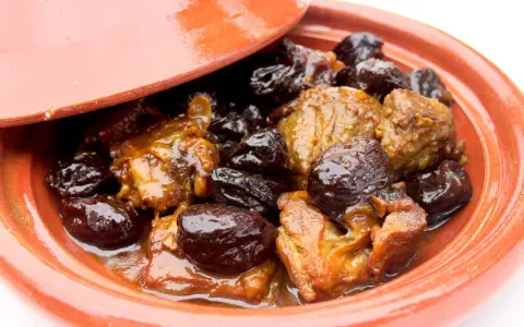 Un plat de tajine aux pruneaux, avec des morceaux de viande mijotés dans une sauce onctueuse et des pruneaux moelleux.