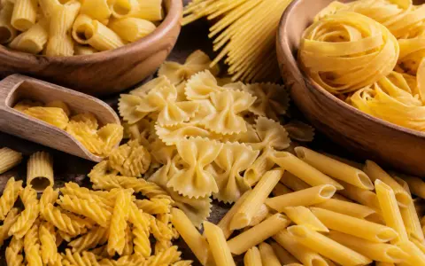 Assortiment de pâtes italiennes : fusilli, farfalle, penne, rigatoni et spaghetti, évoquant la qualité de la farine pour pâtes italiennes.