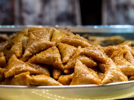 Un plateau rempli de délicieux triangles dorés, un dessert marocain traditionnel, parsemé de graines de sésame.