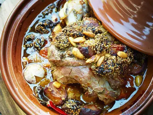 Un plat de tajine agneau aux pruneaux, amandes et sésame, mijotant dans sa sauce parfumée.