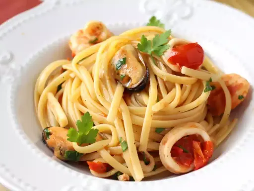 Spaghetti aux fruits de mer à la crème, garni de moules, crevettes, calamars, tomates cerises et persil frais. Un délice crémeux et savoureux.
