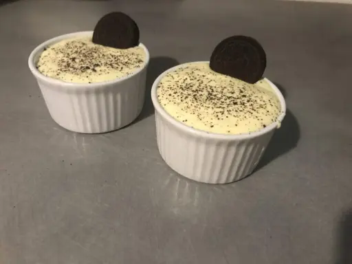 Deux ramequins de tiramisu Oreo, saupoudrés de miettes de biscuit et ornés d'un Oreo entier.