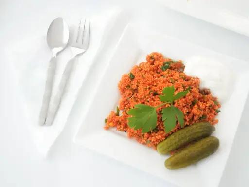 Un plat de boulgour coloré, garni de persil frais, servi avec des cornichons et une touche de yaourt. La cuisson du boulgour est parfaite pour ce repas.