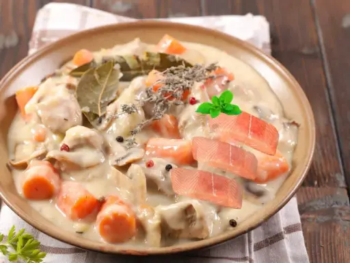 Délicieuse blanquette de poisson crémeuse avec carottes, champignons, herbes et garnie de tranches de saumon frais.