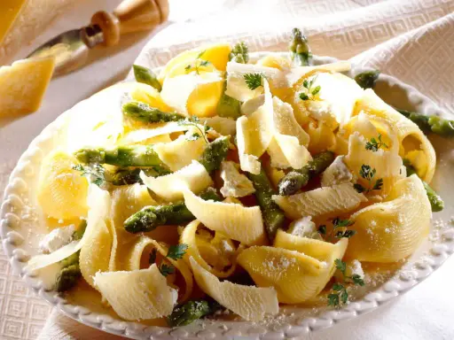 Pâtes aux asperges, garnies de copeaux de parmesan et de persil frais. Un plat printanier savoureux.