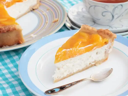 Tranche de cheesecake aux pêches, une gourmandise légère. L'agar agar, son utilisation, assure une texture parfaite.