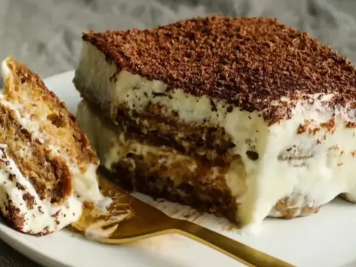 Un morceau de tiramisu, dessert aux origines italiennes, avec ses couches de biscuits imbibés et de crème onctueuse, saupoudré de cacao.