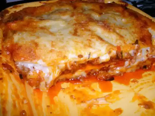 Une part généreuse de lasagne à la viande hachée, avec sa couche de fromage gratiné et sa sauce tomate débordante. Un délice réconfortant.