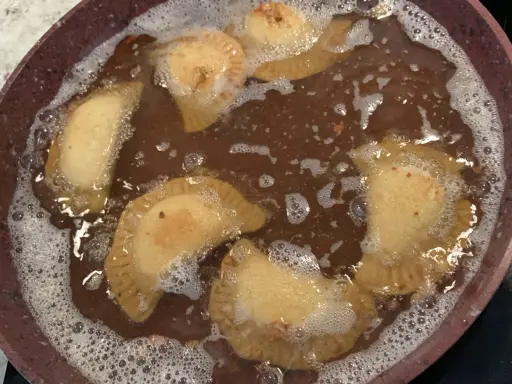 Des samboussek au fromage dorent dans l'huile chaude, formant des bulles joyeuses.