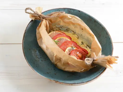 Poisson cuit en papillote avec tomates et citron, une recette bar simple et savoureuse.