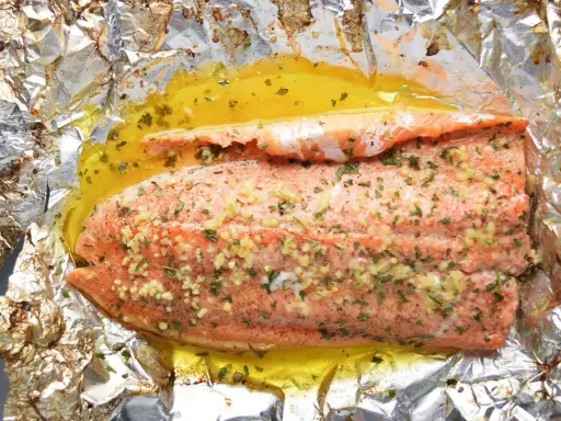 Filet de truite cuit en papillote, assaisonné d'ail et d'herbes, baignant dans un jus doré. Une recette simple et savoureuse.