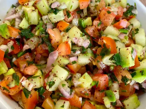 Salade marocaine fraîche et colorée, mélange de tomates, concombres, oignons rouges et persil, assaisonnée d'épices.