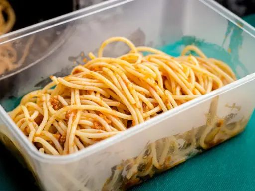 Boîte transparente remplie de spaghettis à la sauce bolognaise, idéale pour la conservation des pâtes cuites.