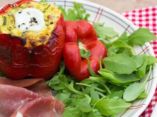 Poivrons farcis à l'italienne, garnis d'une préparation savoureuse et surmontés d'une touche de crème fraîche. Servi avec roquette et fines tranches de jambon.
