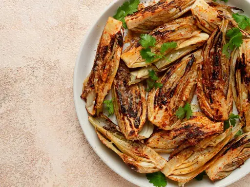 Fennouil rôti, coupé en quartiers, assaisonné et garni de coriandre fraîche. Une belle façon de cuisiner le fenouil pour un plat savoureux.