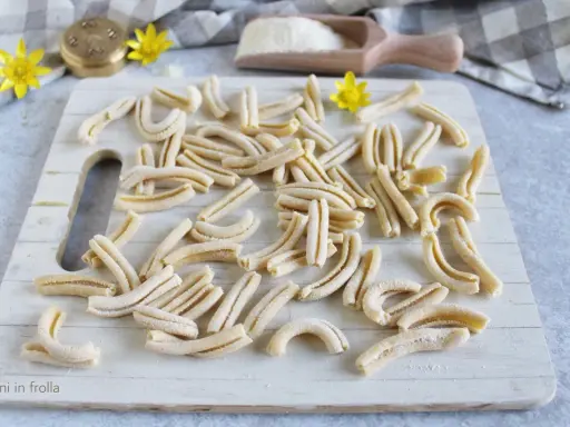 Des pâtes fraîches, prêtes à être cuites. Un aperçu de comment faire des pâtes maison, avec un rouleau à pâtes et de la farine.