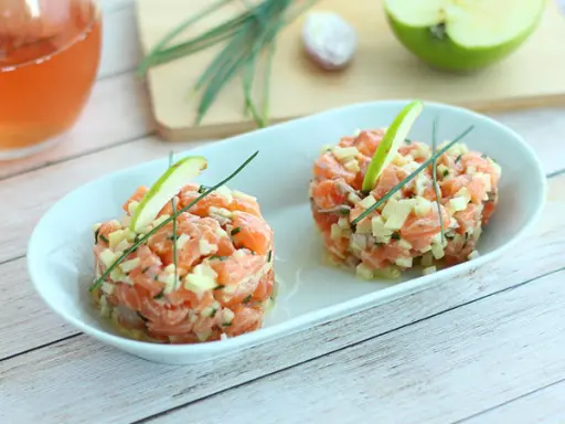 Deux tartares de saumon frais, garnis de dés de pomme verte et de ciboulette, parfaits pour une recette saumon fumé revisitée.