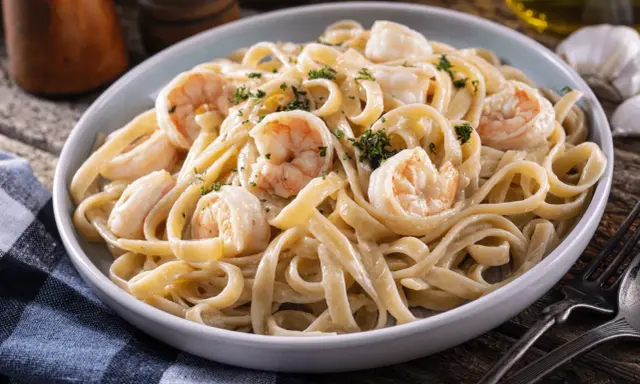Délicieuses pâtes aux crevettes, une recette italienne crémeuse et savoureuse, garnie de persil frais.
