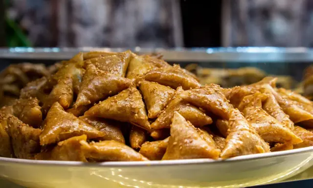 Un plateau rempli de délicieux triangles dorés, un dessert marocain traditionnel, parsemé de graines de sésame.