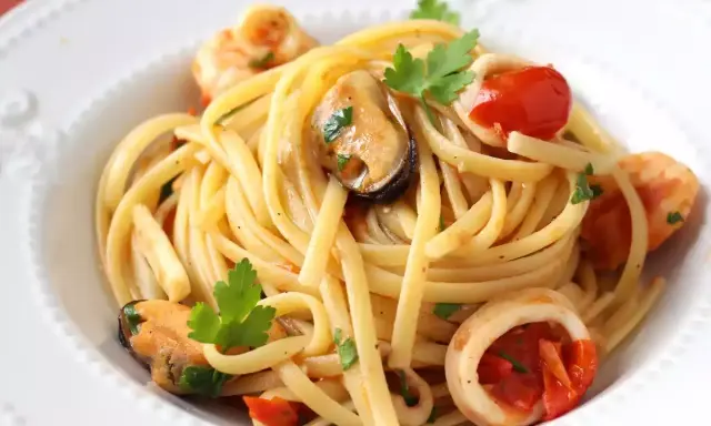 Spaghetti aux fruits de mer à la crème, garni de moules, crevettes, calamars, tomates cerises et persil frais. Un délice crémeux et savoureux.