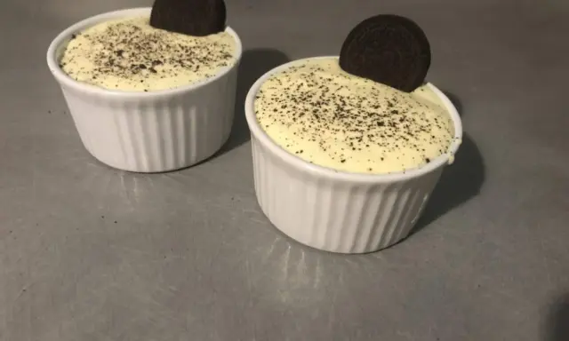 Deux ramequins de tiramisu Oreo, saupoudrés de miettes de biscuit et ornés d'un Oreo entier.