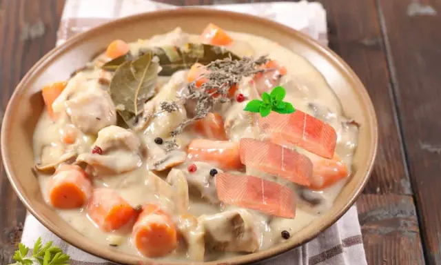 Délicieuse blanquette de poisson crémeuse avec carottes, champignons, herbes et garnie de tranches de saumon frais.