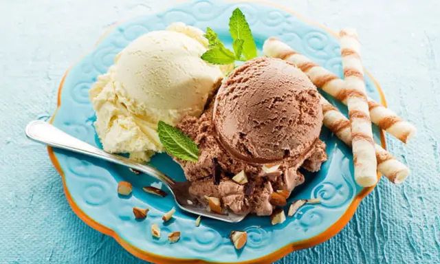 Glace italienne maison sans machine : deux boules vanille et chocolat, garnies d'amandes et de menthe, avec des gaufrettes.