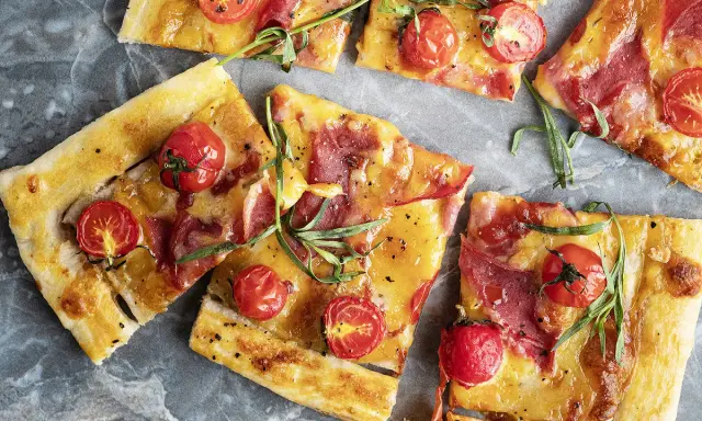 Délicieuse recette salée avec pâte filo : tartes fines garnies de tomates cerises, fromage fondant et fines tranches de charcuterie, parsemées d'herbes fraîches.