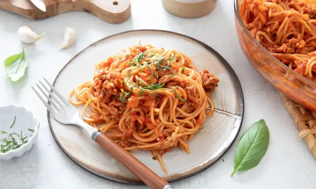 Une assiette de spaghetti à la bolognaise, plat réconfortant de one pot pasta, garnie d'herbes fraîches.