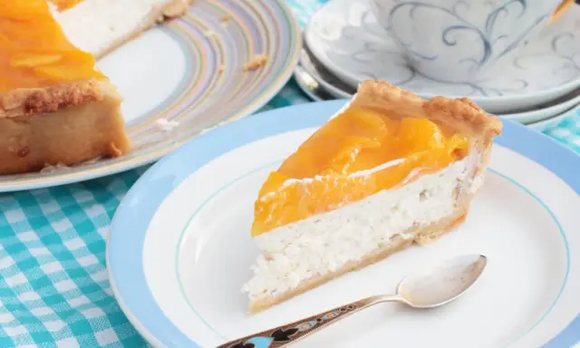 Tranche de cheesecake aux pêches, une gourmandise légère. L'agar agar, son utilisation, assure une texture parfaite.