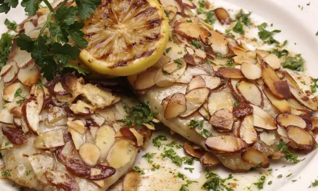 Délicieuse truite aux amandes au four, garnie d'une tranche de citron grillé et de persil frais.