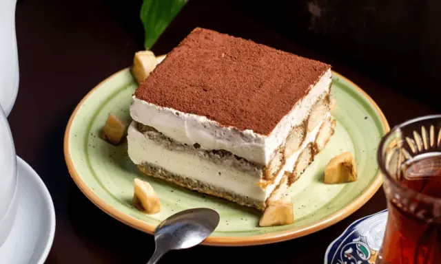 Un tiramisu onctueux, saupoudré de cacao, servi avec des morceaux de fruits. Une idée pour par quoi remplacer le café dans le tiramisu ?